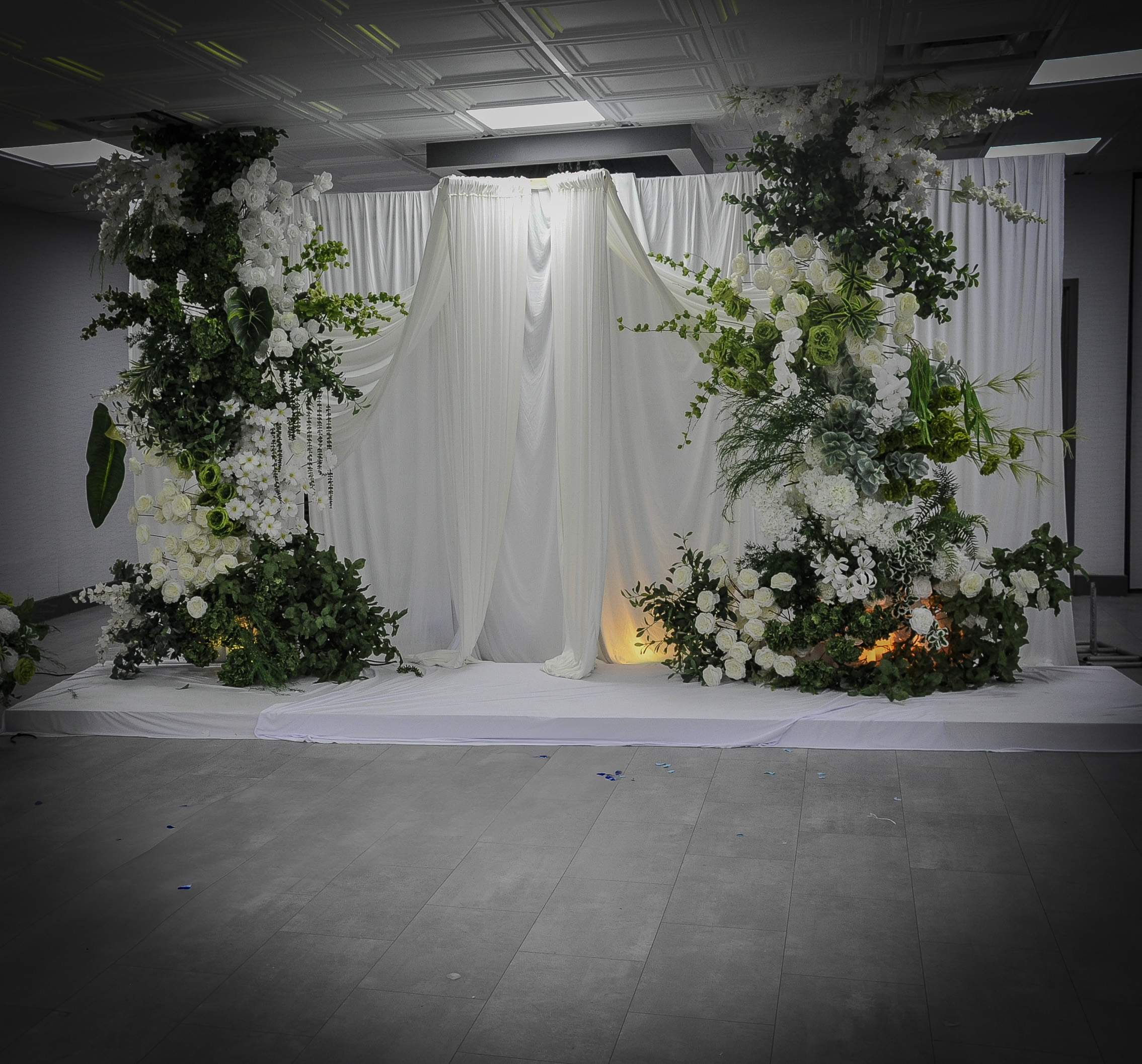 White draped ceremony backdrop with lush floral columns